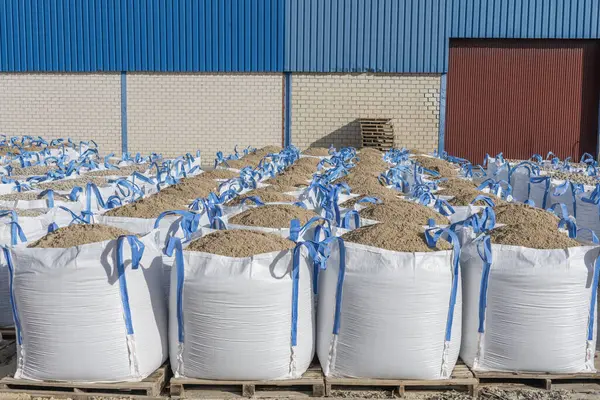 İnşaat için kum dolu bir sürü büyük raffia torbası.