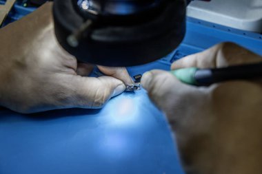 Elektronik mağazasında bir tamir teknisyeni bir USB kablosu lehimlemeye çalışıyor.