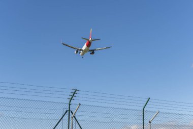 Havaalanı pistine inmek için iniş takımlarını indiren bir yolcu uçağı.