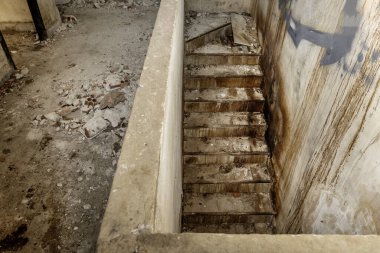 Aşağıda enkaz ve kirle dolu harabe bir binada.