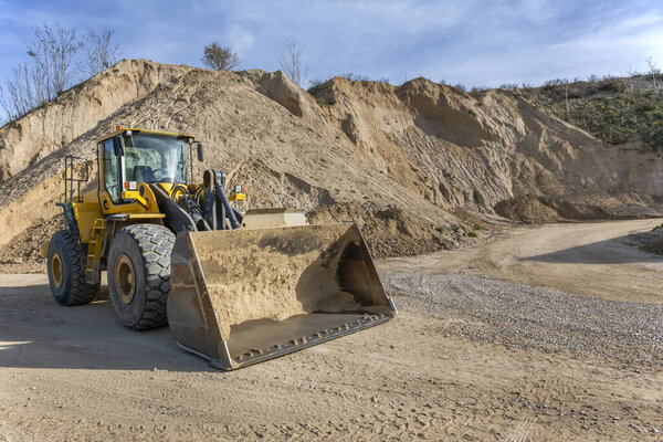 Self-supported construction machinery standing next to large mounds of river sand