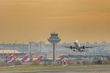 Türbinleri tam güçte olan bir yolcu uçağı havalimanı kontrol kulesinin yakınından kalkışta irtifa kazanıyor.