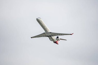 Gri gökyüzünü boydan boya geçen bir yolcu uçağı.