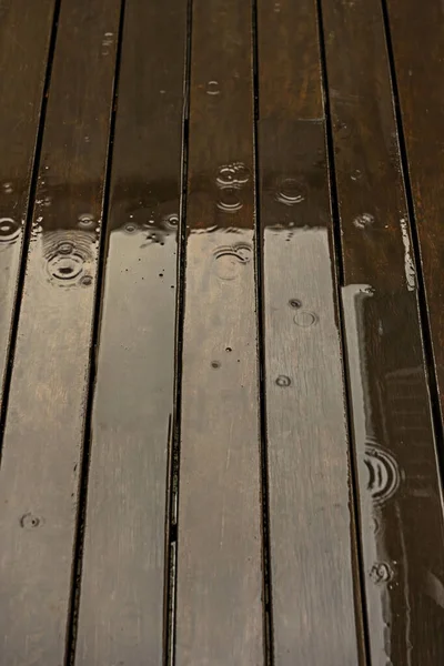 of the waves produced by water drops on the wooden plank floor of a terrace filled with rainwater on a winter day