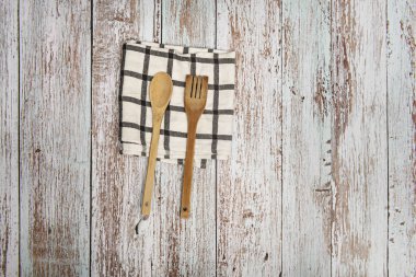 Ahşap bir yüzey üzerinde gri çizgileri olan beyaz bir bez üzerinde ahşap mutfak gereçleri.