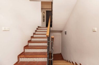 Çeşitli yüksekliklerde tek kişilik ev merdivenleri tahta kenarlı taş kaplama merdivenler ve tırabzanlı metal korkuluklar.