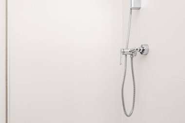 Pürüzsüz beyaz duvarları olan bir banyoda krom musluklar