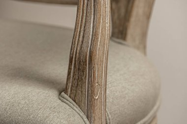 Gri döşemeli, verniklenmemiş ahşap bir koltuğun yakın çekimi.