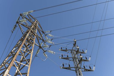 Kablolarından elektrik taşıyan bazı yüksek voltajlı kuleler. Açık gökyüzü olan güzel bir günde çan yalıtıcılarıyla.