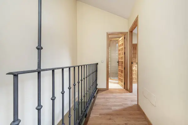 Interior staircase of a duplex residential house with metal wrought railings and Castilian style wooden panel doors