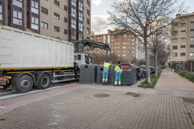 Kamyon vinci ile cam kapları ve geri dönüşümlü malzemeleri kaldıran belediye çalışanları
