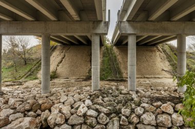 Bir yol köprüsünün altında dairesel beton sütunları olan iki bağımsız ceset var.