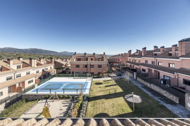 Yüzme havuzları, çocuk oyun alanları ve şemsiyeli çimenlikleri olan iç ortak alanları olan çeşitli yüksekliklerdeki yarı müstakil tek aile evlerinin kentleşmesi