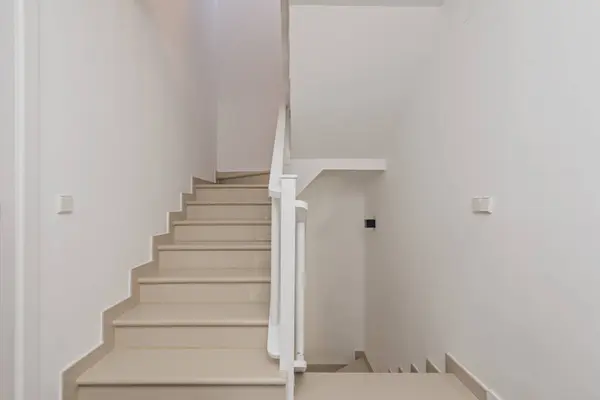 Several flights of stairs in a single-family home of various heights with white painted metal railings, synthetic stone steps and plain white painted walls