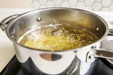 100 santigrat derecede kaynayan suyla dolu paslanmaz çelik bir kap.