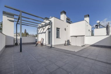 Zemini aydınlık, tenteli olmayan bir çatı katı, açık gökyüzü olan bir günde gri taş kaplama döşeme.