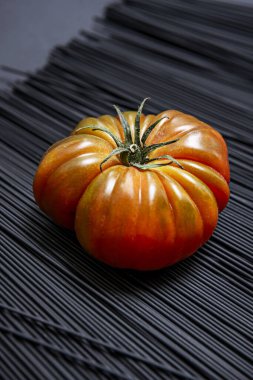 A succulent ripe Raf tomatoes on a black tinted spaghetti clipart