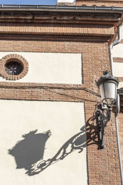 Katolik kilisesinin ön cephesinde dökme demir kollu klasik bir lamba.