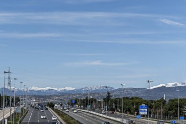 Sierra de Navacerrada 'nın karlı dağının yanındaki ormanın yanında bir otoyol.