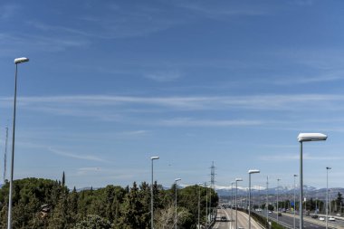 Karlı dağ istikametindeki bir ormanın yanında yol ve karayolu aydınlatan sokak lambaları.
