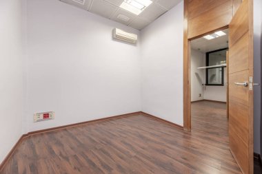 Sade beyaz duvarları, kırmızı parke zemini ve teknik tavanı olan boş bir ofis.