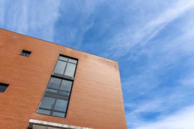 Güzel mavi gökyüzünün olduğu bir günde açık kahverengi tuğlalı bir binanın alçak açılı görüntüsü.