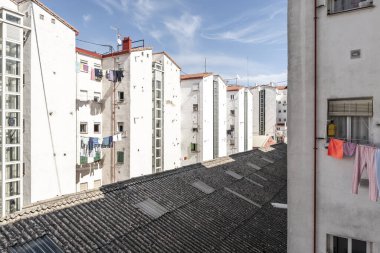 Bir bloğun iç avlusunda beyazlatılmış binalar ve merkezi bir uralite çatısı muhtemelen asbest içeriyor.