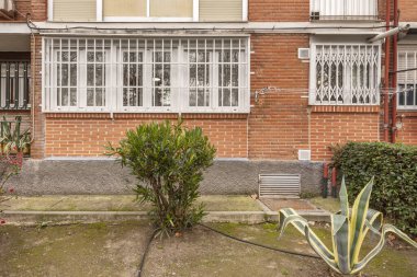 Pencerenin altında bahçesi olan geleneksel tuğla bina cepheleri.