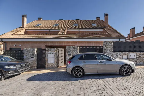 Yarı müstakil evlerin cephelerinde taş duvarlar ve caddeye park edilmiş araçlar var.