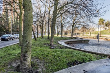 Kentsel bir gezinti alanında ağaçların ve taş koltukların olduğu bahçe alanları