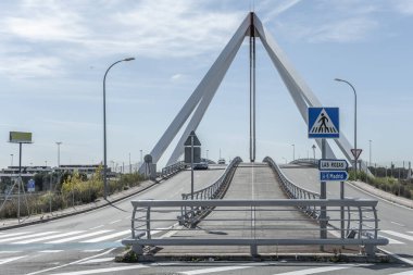 Küçük bir köprünün metal yapısı kaldırımda dikey ve yatay olarak yol trafiğine işaret ediyor.