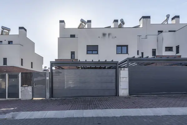 Facades of semi-detached houses in a modern minimalist style with gray garage access doors