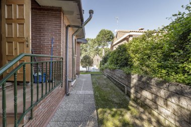 Tuğla cepheli müstakil bir evin etrafında fayanslı bir patika olan çevre bahçesi.