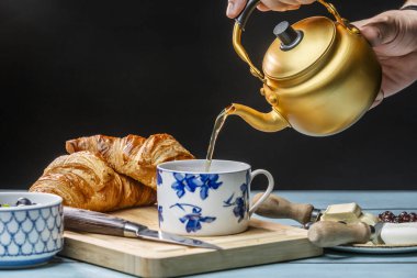 Bir fincan çayı yanında bir sürahi meyve, tereyağı ve kruvasanla dolduruyorum.