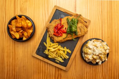 Bal rengi çam ağacından bir masa, tahta bir tabak kakao ve iki kase patatesle destekleniyor.