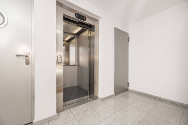 Beyaz boyalı duvarları ve paslanmaz çelik asansörü olan bir eve.