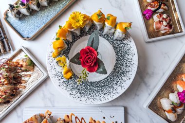 Gökkuşağı Yuvarlak: Uramaki 'nin üzerinde ince şeritler halinde kesilmiş çeşitli çiğ balıklar var