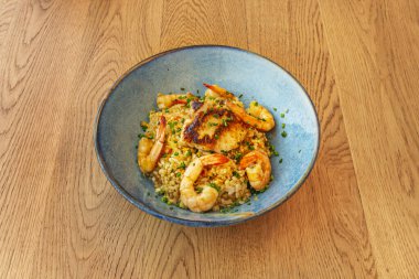 İçinde kabuklu karides dolu deniz ürünleri pilavı tarifi olan güzel bir mavi kase. 