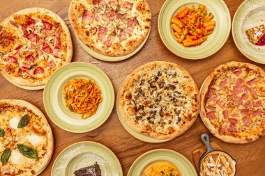 Güzel ahşap bir masa pizzalarla ve tipik İtalyan yemekleriyle doludur.
