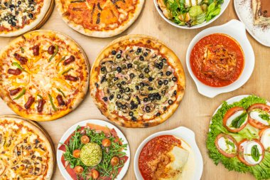 Bir masa dolusu pizza ve tipik İtalyan yemekleri.