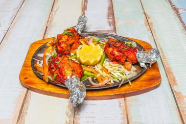 Tavuk yoğurtta terbiye edilir ve tandır masala baharat karışımıyla terbiye edilir, garam masala da eklenir..