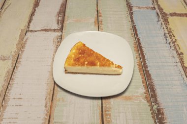 Basit beyaz tabakta küçük bir dilim cheesecake.