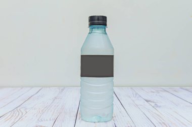 Küçük, mavimsi berrak plastik bir su şişesi beyaz bir masada.