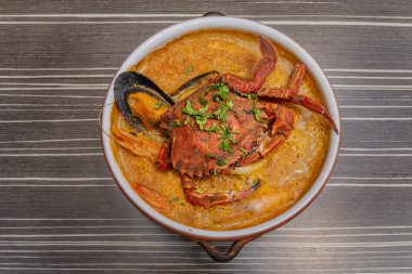 Genellikle deniz ürünleri ve et suyu bazlı kilden bir tencerede yapılır. 