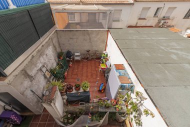 İçinde bazı bitkiler olan küçük bir iç avlu resmi, asma ipleri ve açık hava dolapları.