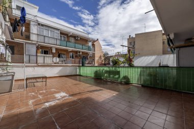 Üst katlarda koyu terasotta döşemeleri ve balkonları olan bir evin iç avlusu.