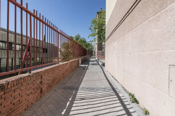 Bir tarafında kırmızı metal çit olan dar bir yol.