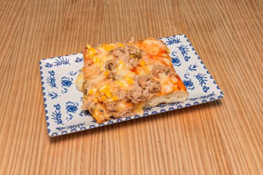 Pizzayı dilimle. Büyük dikdörtgen tavalarda pişirilip ağırlıkla satılan hamur genellikle gevrek bir tabanı ve yumuşak bir iç yapısı olan yuvarlak Roma pizzasından daha kalın ve havalıdır.