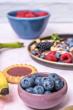 Yaban mersini ve diğer böğürtlenler ahşap bir kasede karıştırılarak, kırmızı ve beyaz tonlarda bir karşıtlık yaratır.