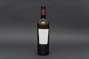 Görünüşünü ve şeffaflığını arttıran tek bir şarap şişesinin mat siyah arka plan üzerindeki minimalist kompozisyonu.